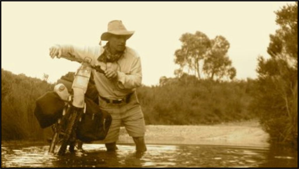 Bernie Harberts pushing his $10 bike through a creek in Tasmania